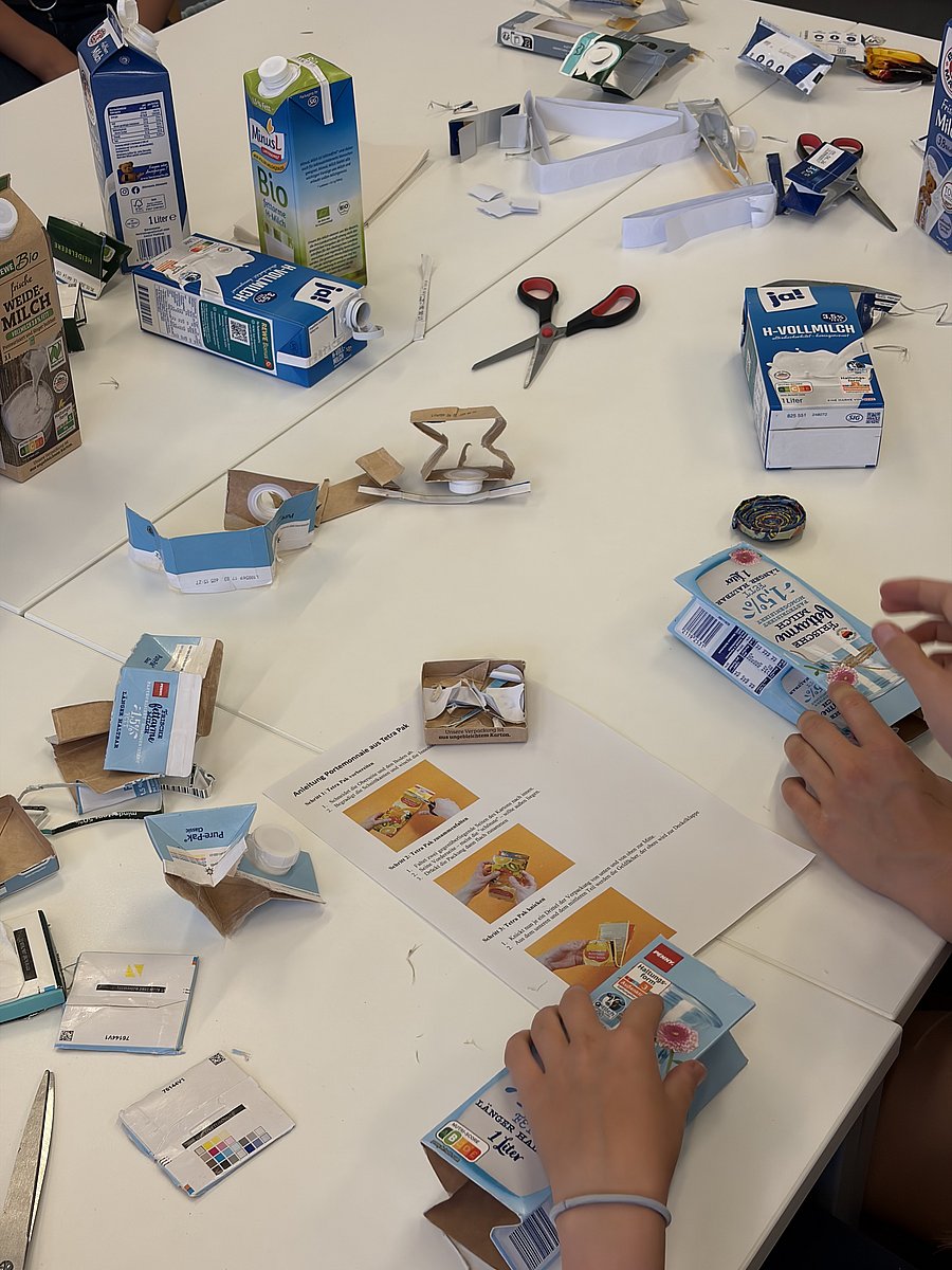 Tisch mit Utensilien für ein Upcycling-Projekt (Geldbörse aus einem alten Tetra Pak herstellen)