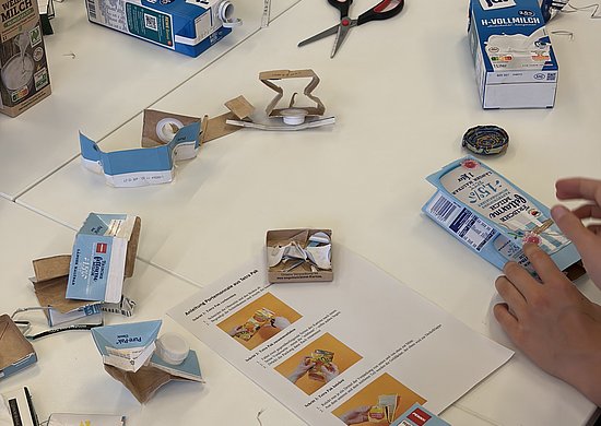 Tisch mit Utensilien für ein Upcycling-Projekt (Geldbörse aus einem alten Tetra Pak herstellen)